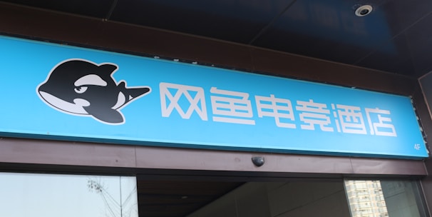 A building entrance features a vibrant blue sign with white Chinese characters and a stylized orca logo in black and white. The overall appearance suggests an establishment focused on eSports or digital activities.
